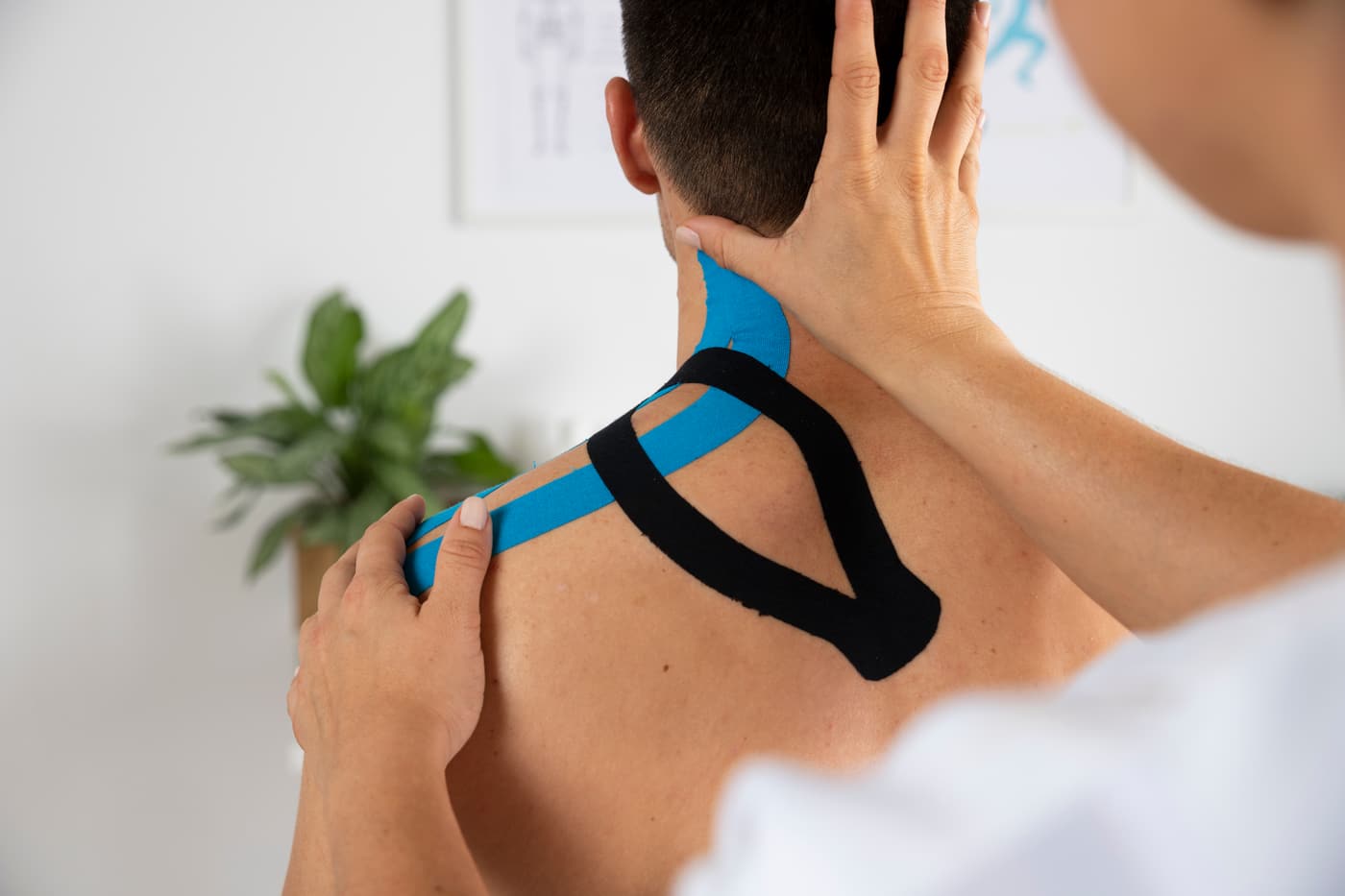 Kinesiology tape applied across a patient's upper back and neck